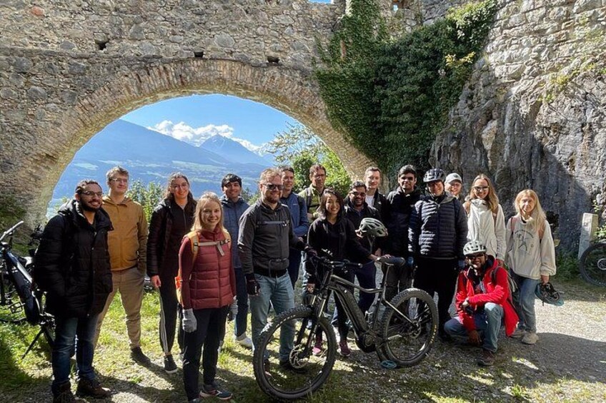 Un gruppo di persone in piedi di fronte a un arco in pietra, con una montagna sullo sfondo. 4