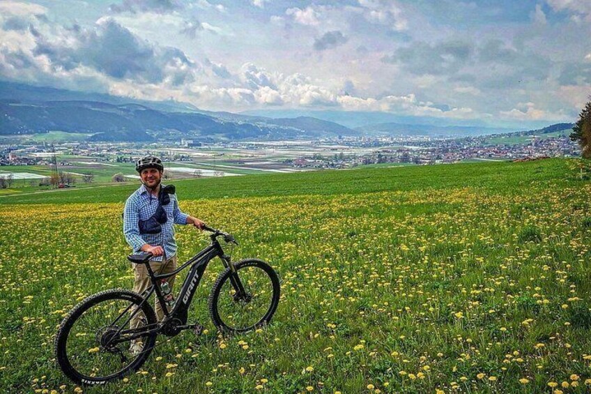 Una persona en bicicleta en un campo de flores amarillas, con un paisaje urbano al fondo. 4
