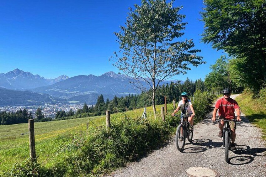 Two cyclists on a gravel path with a scenic mountain view in the background. 1