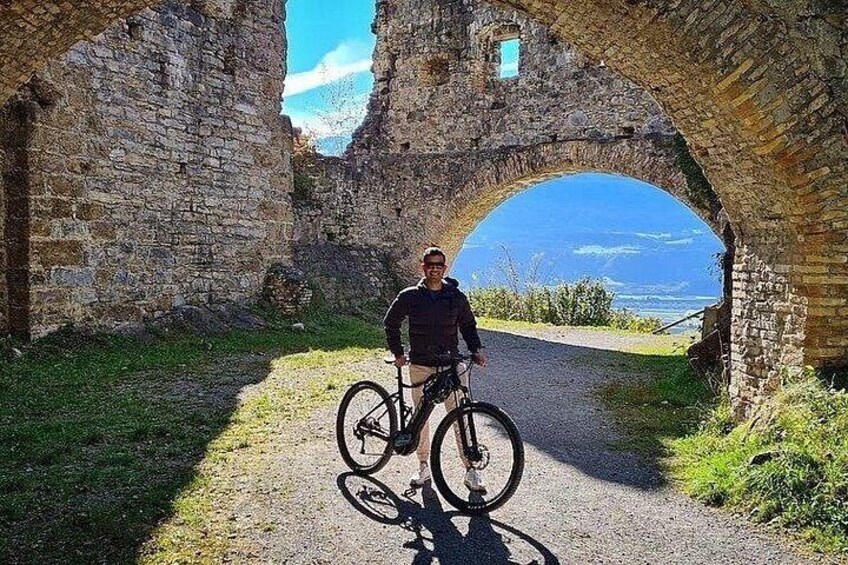 Una persona parada bajo un arco de piedra con una bicicleta. 2