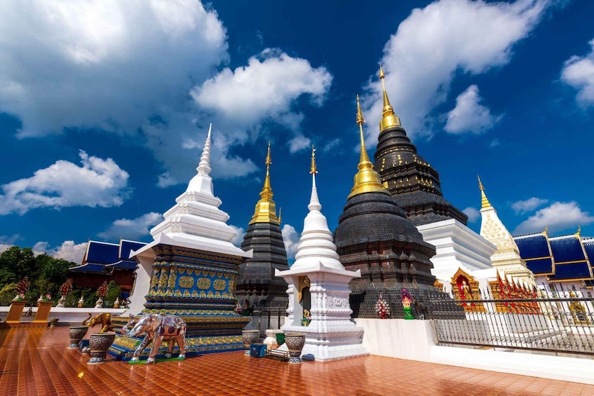 A temple complex with multiple spires, some white and others black with gold accents, under a clear blue sky. 2