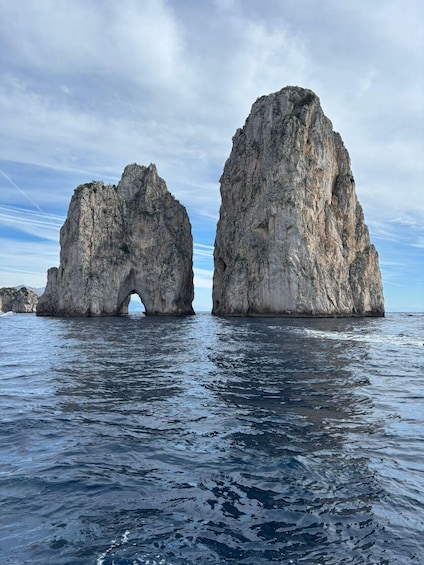 Two large rock formations with a natural archway in the middle, surrounded by calm sea water. 1