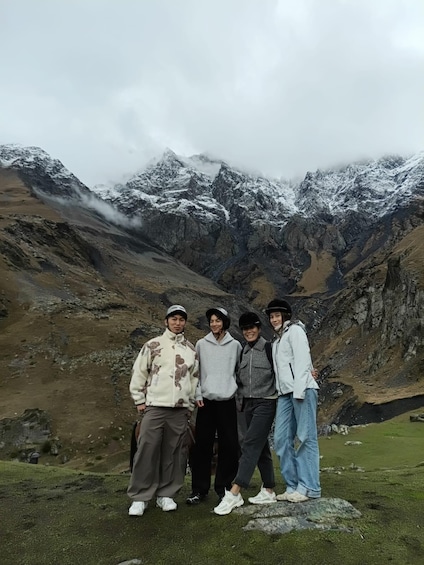 A group of people standing on a grassy area with a mountainous landscape in the background. 3