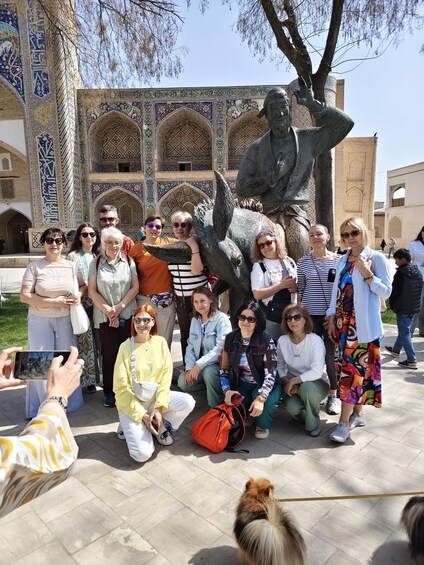 A group of people posing in front of a historical building with intricate tile work and a large statue. 2