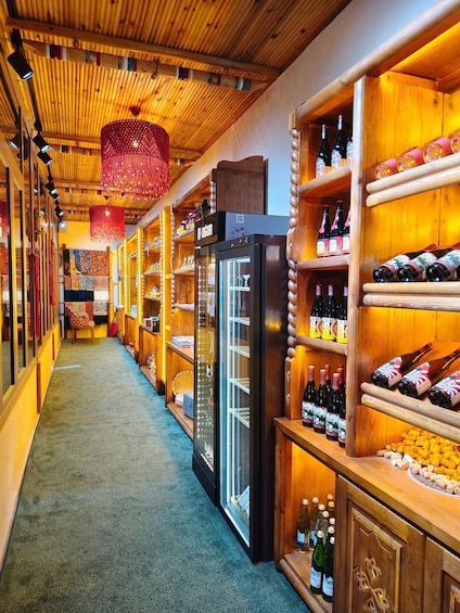 A wooden interior with shelves of wine bottles and a refrigerator. 4
