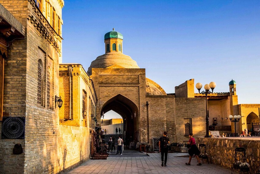 A historic building with a large archway, domed structure, and a tower with a green roof. 1