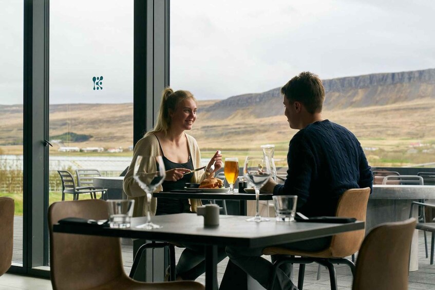 Dos personas cenando en un restaurante al aire libre con vistas a un paisaje montañoso. 2