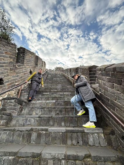 Two people climbing a stone staircase with a cloudy sky in the background. 3