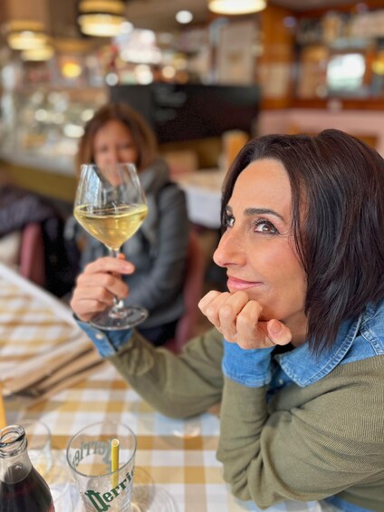 Une personne tenant un verre de vin à une table de restaurant. 1