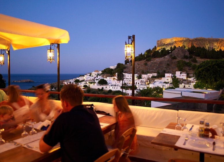 A restaurant overlooking a coastal town with white buildings and a castle on a hill. 1