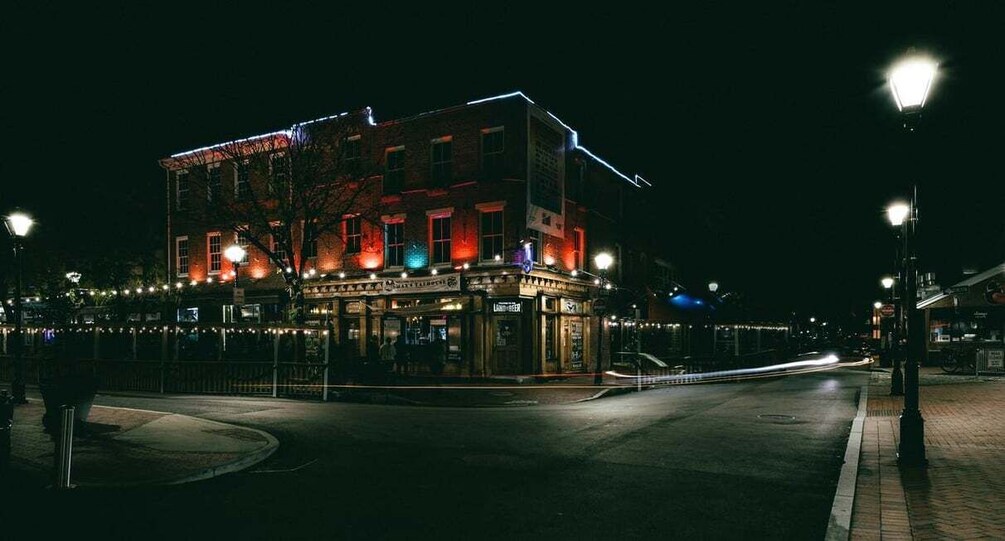 A brightly lit building with a corner entrance, street lamps, and a paved sidewalk. 2