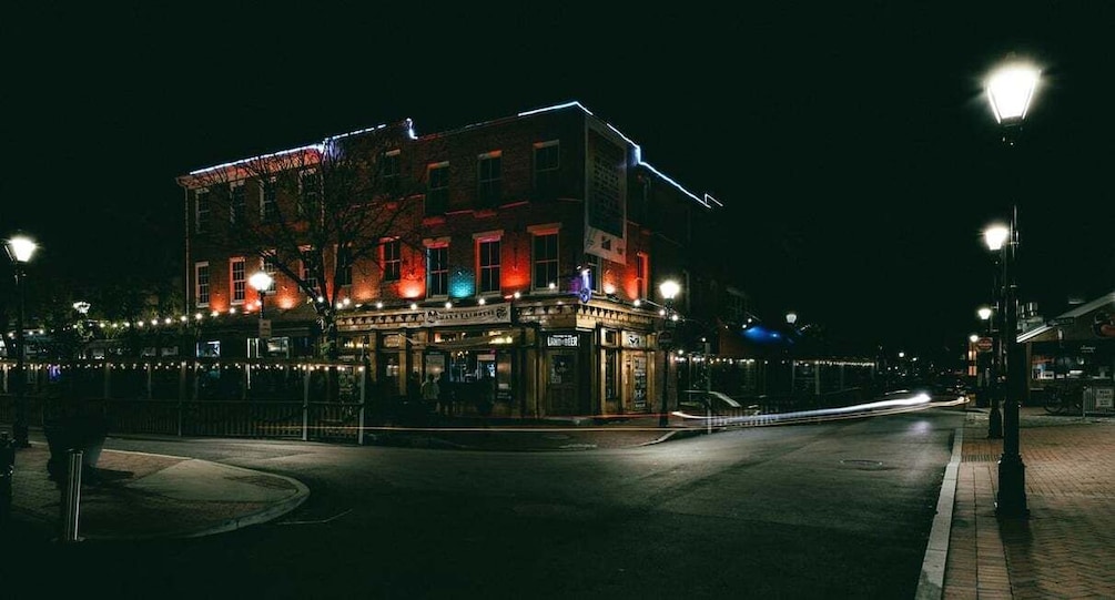 A brightly lit building with illuminated windows and a street corner at night. 2