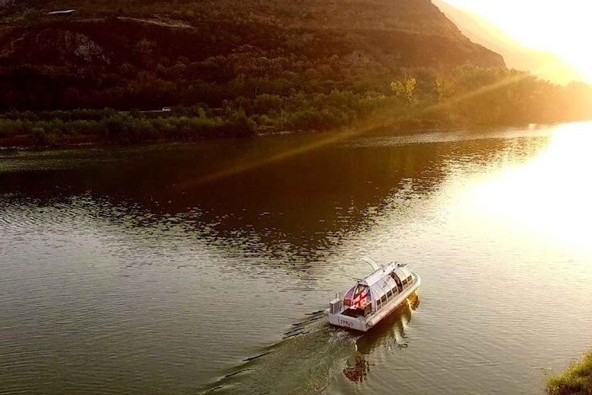 Un bote navegando por un río, con un paisaje montañoso al fondo. 5