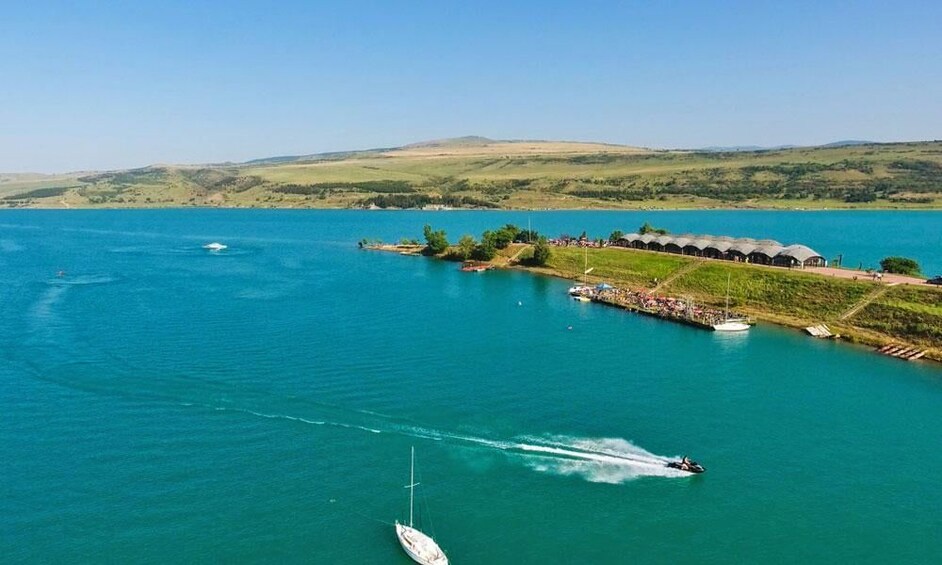 Un lago con un bote, un jet ski y un muelle con edificios. 4