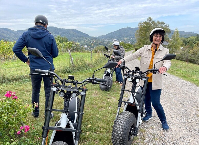 Trois personnes se tiennent sur un chemin de gravier, à côté de trottinettes électriques. 5