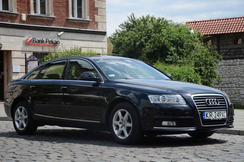 Ein schwarzer Audi parkt vor einem Gebäude, an dem ein Schild mit der Aufschrift 'Bank Pekao' angebracht ist. 3