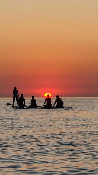 Atardecer sobre el océano con gente haciendo paddleboard. 5