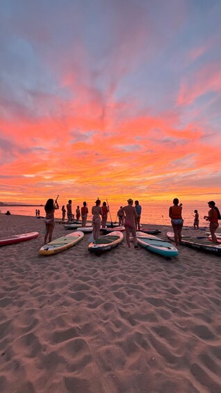 A beach at sunset with people paddleboarding. 5