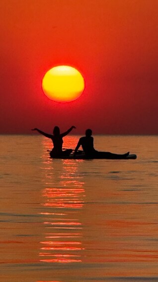 Dos siluetas de personas sentadas en un bote al atardecer. 1