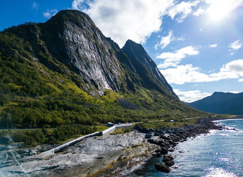 A coastal road with a mountain backdrop, a bridge, and a clear sky. 5