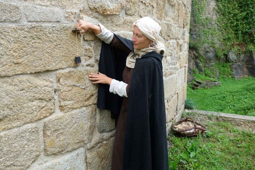 A person in historical attire interacting with a stone wall, possibly a medieval or renaissance setting. 5