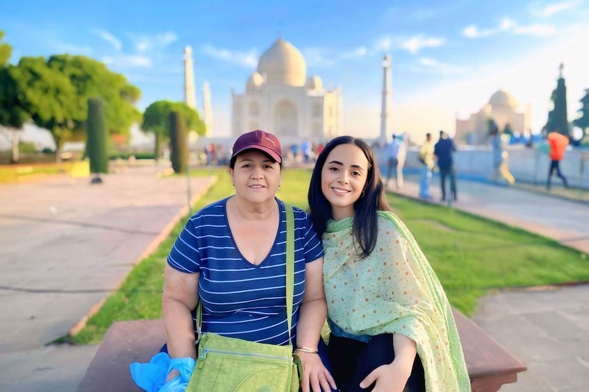 Dos personas sentadas en un banco con el Taj Mahal al fondo. 1