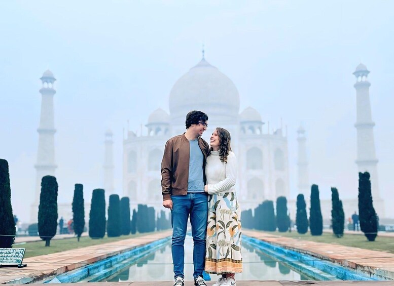 Una pareja de pie frente al Taj Mahal, con una vista despejada de las icónicas cúpulas y minaretes. 4