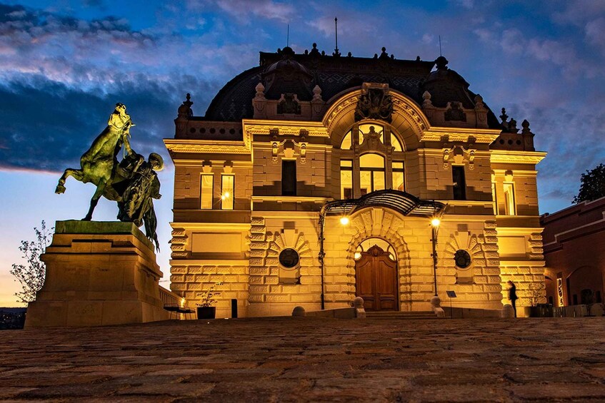 A grand building with a dome and arched windows, illuminated at dusk. 2