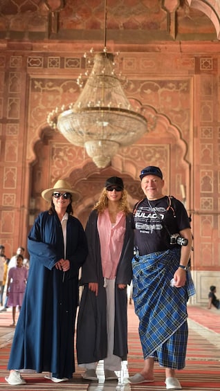 A group of people in a historic building with intricate architecture and a large chandelier. 4