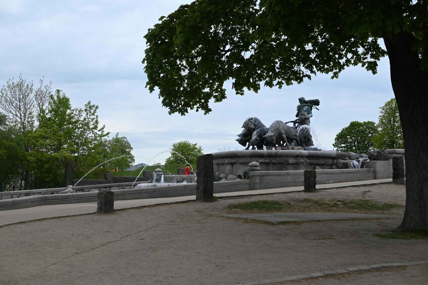 A park with a statue of a horse and rider, surrounded by trees and a fountain. 2