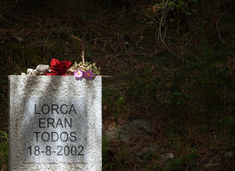 En gravsten med inskriptionen ”LORCA ERAN TODOS 18-8-2002”, omgiven av blommor. 1