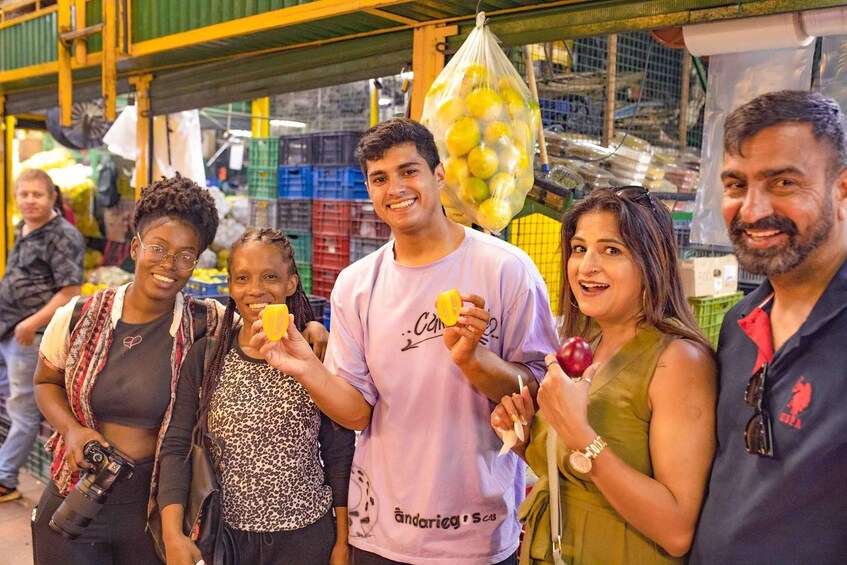 A group of people at a market with various fruits and vegetables on display. 2
