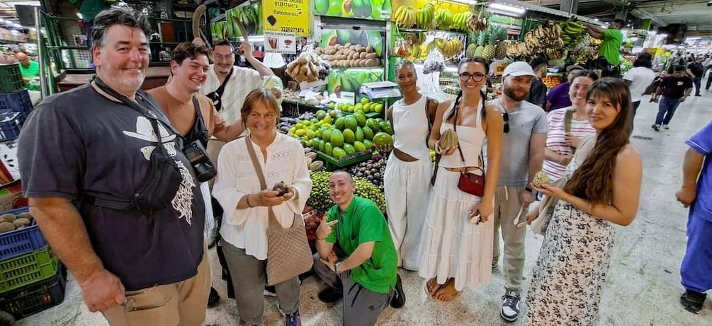A group of people shopping in a market with various fruits and vegetables on display. 2
