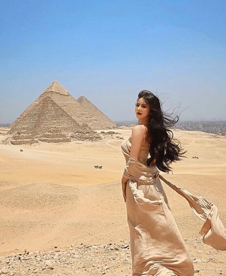 En person i en flydende kjole med en pyramide i baggrunden. 3