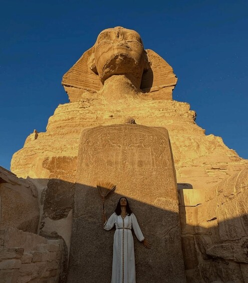 En person står foran Sfinksen i Giza med en kost. 5