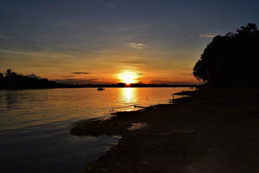 A sunset over a calm river with boats and a distant shoreline. 2