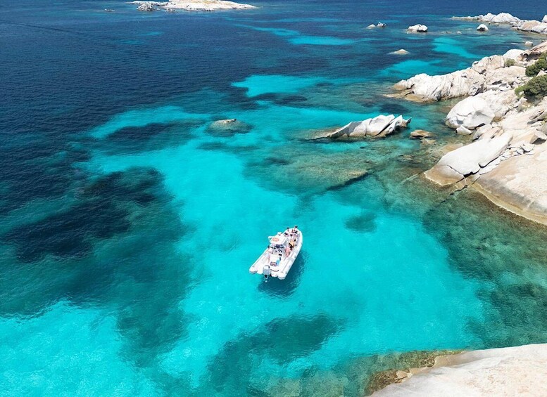 A boat on clear turquoise waters surrounded by rocky terrain. 1