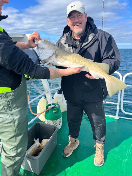 A person holding a large fish on a boat. 5
