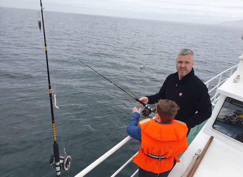 A man and a child fishing on a boat with calm sea and overcast sky. 1