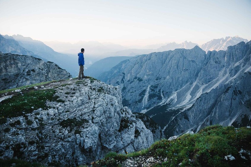 A person standing on a rocky mountain peak overlooking a valley. 5