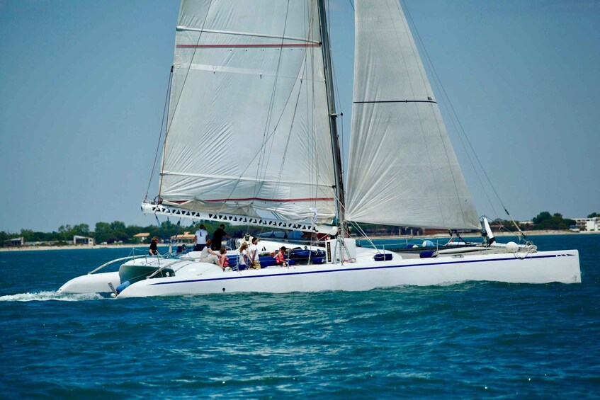 A sailboat with multiple passengers on a calm sea. 5