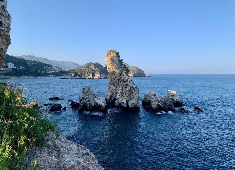 A coastal landscape with prominent rock formations and a distant mountain range. 4