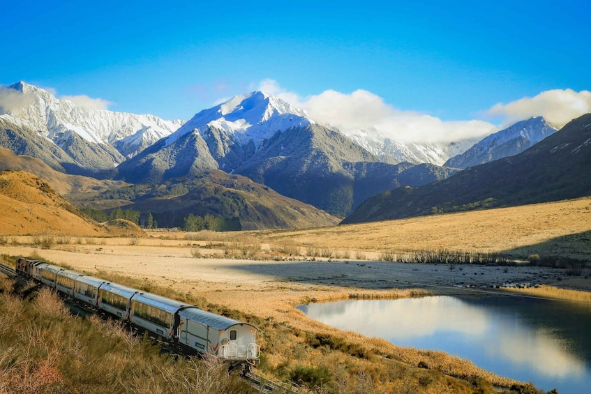 A train traveling through a valley with mountains in the background. 5