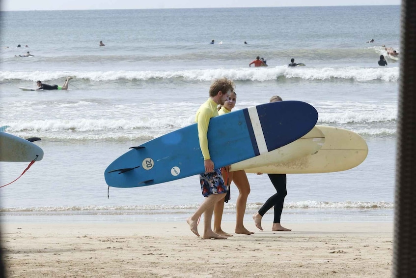 A beach with people walking and carrying surfboards. 3