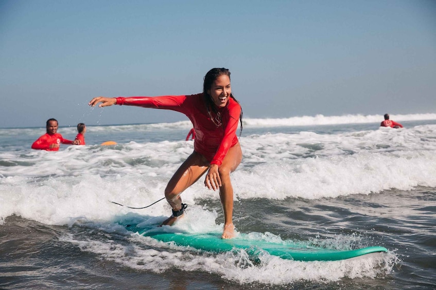 A person surfing on a green board in the ocean. 2