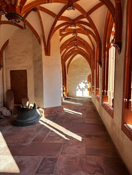 A stone corridor with arched ceilings and a large wooden shoe on the floor. 1