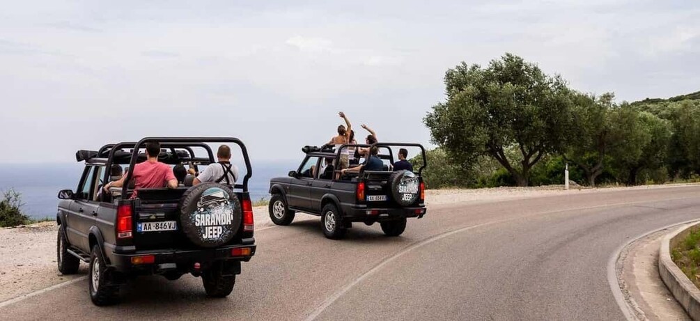 Two off-road vehicles on a winding road with a coastal view. 5