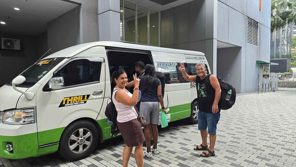 A white van with 'THRILL ADVENTURES TRAVEL & TOURS' written on it, parked in front of a building with a gated entrance. 4