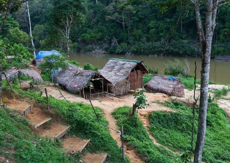 A rural village with thatched-roof huts by a river. 2