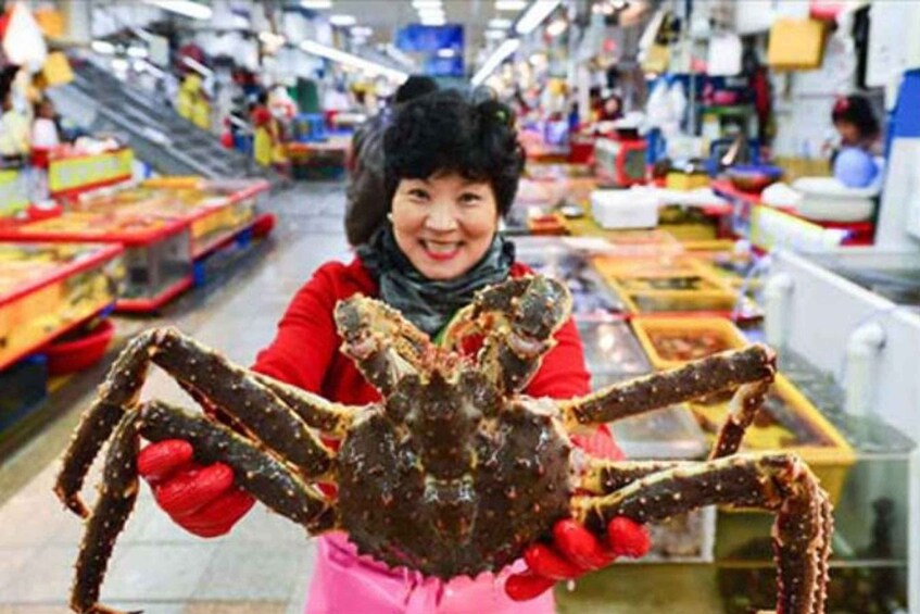 A person holding a large crab in a market. 2